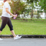 Orang-orang berjalan kaki di taman dengan latar belakang pepohonan hijau.