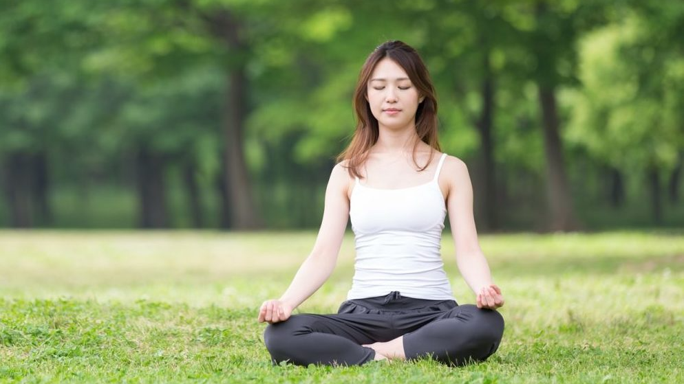 Orang sedang meditasi di lingkungan alam yang tenang